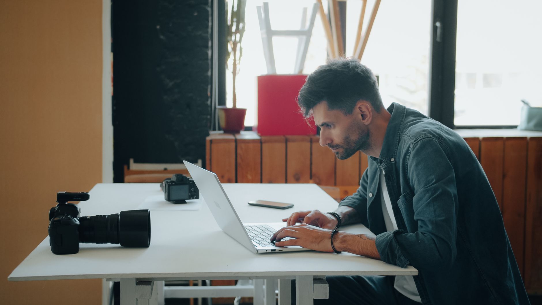 Laptop e smartphone lado a lado numa mesa, representando a comparação entre site e redes sociais para fotógrafos